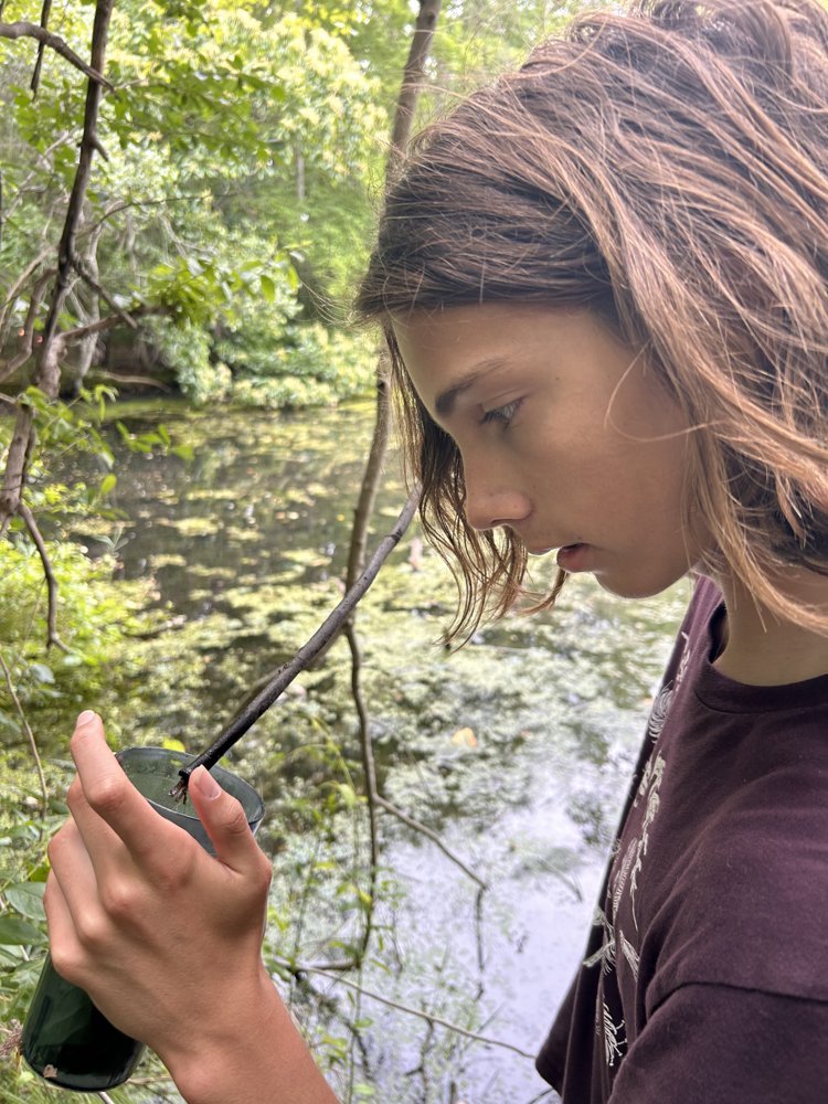 Nico collecting a water sample in the field for research